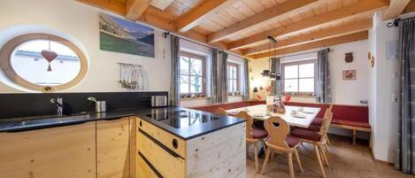 Une cuisine dotée de meubles en bois, d’un îlot central et d’un coin repas avec une table et des chaises.