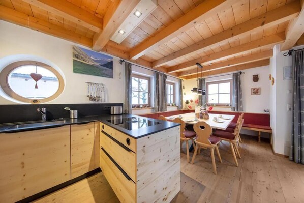 A kitchen with wooden cabinets, a central island, and a dining area with a table and chairs.