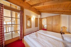 Ein Zimmer mit Bett, Kleiderschrank, Spiegel und einem fenster mit Vorhängen.