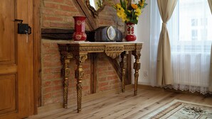 A wooden table with a clock and vases against a brick wall.