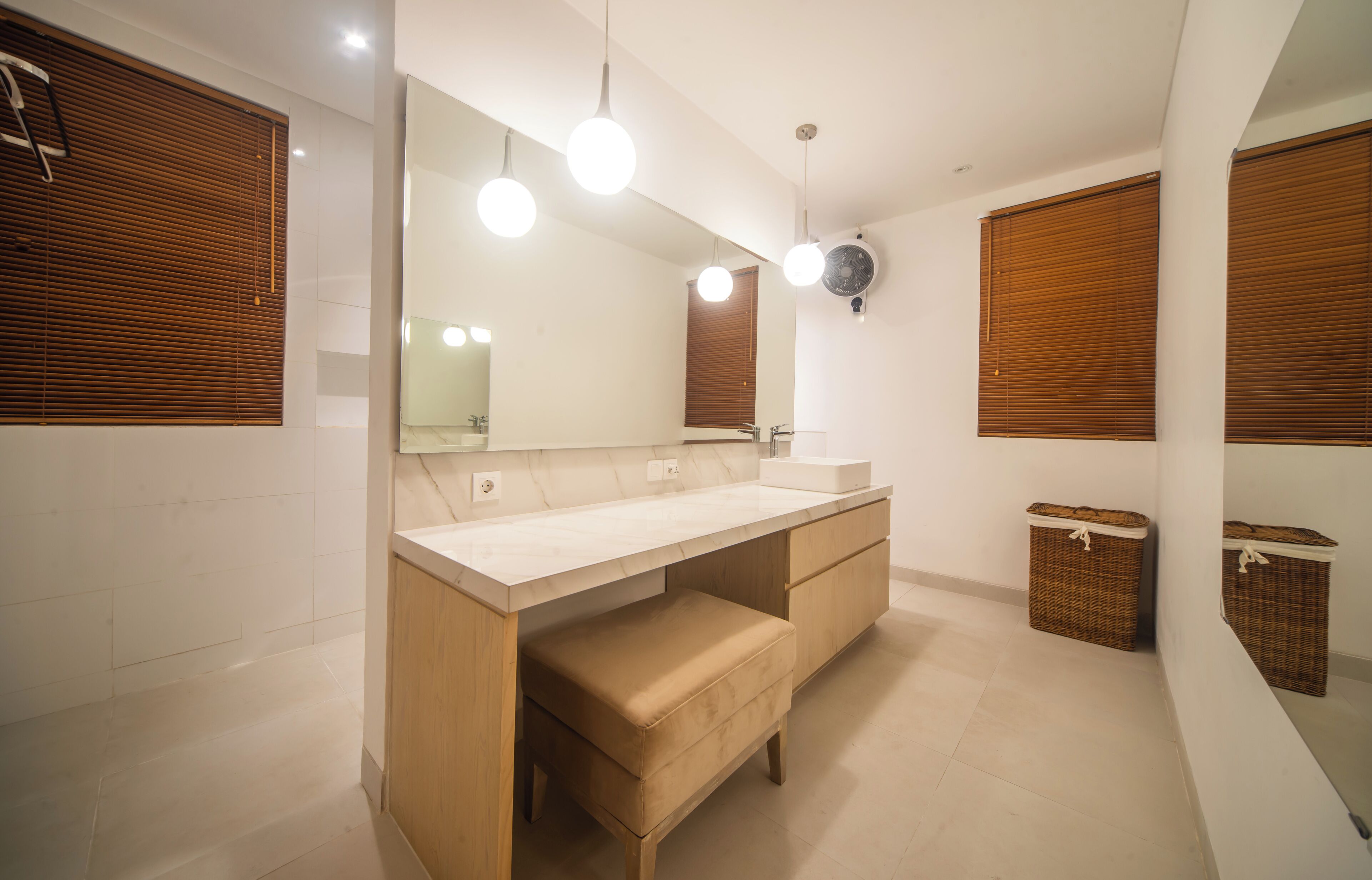 A modern bathroom with a large mirror, wooden vanity, and two wicker baskets.