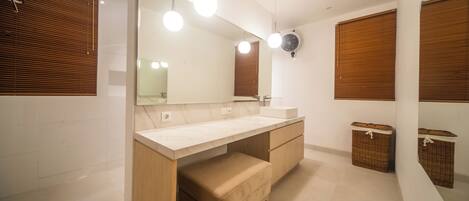 A modern bathroom with a large mirror, wooden vanity, and two wicker baskets.