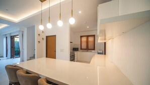 A modern kitchen with a large island, pendant lighting, and a view to the dining area. - Luxury 4 Bedroom Bella Vista Villa (Ungasan)