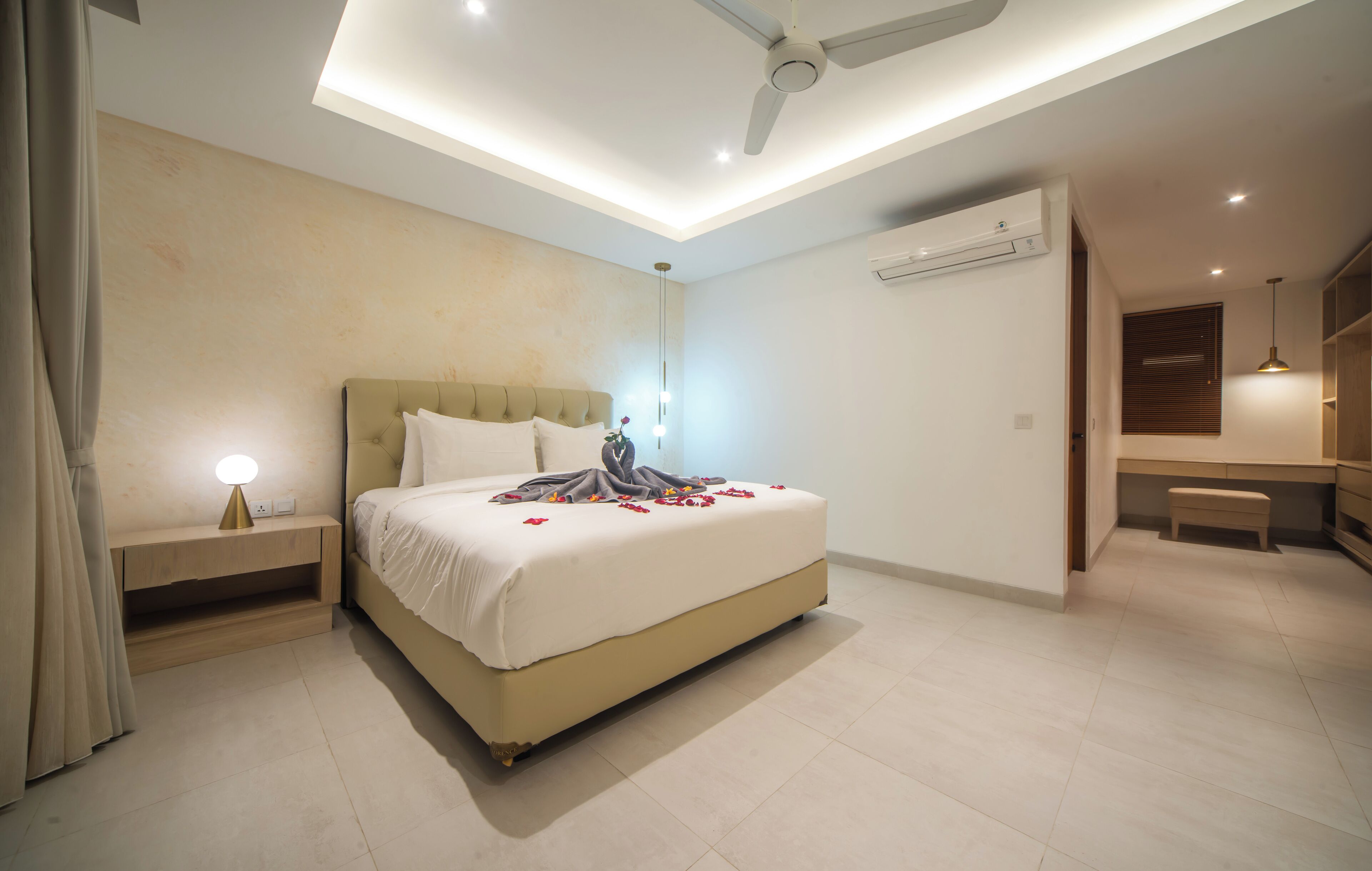 Un dormitorio moderno con cama, mesitas de noche, ventilador de techo y un pequeño banco.
