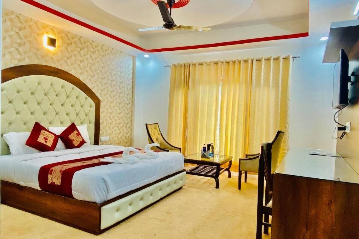 Ein Hotelzimmer mit einem großen Bett, einem Schreibtisch, einem Sessel, einem Fernseher und einem Deckenventilator.