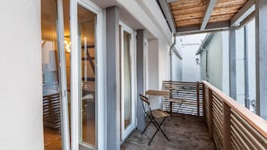 Un balcon doté d’un plancher en bois, d’une rambarde en métal et d’une table avec des chaises.