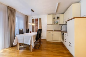 A modern kitchen with white cabinets, a dining table with chairs, and a built-in oven.