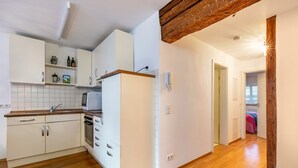 Une cuisine avec des armoires blanches, un plan de travail en bois et un four encastré.