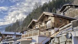 Un chalet en bois doté de plusieurs balcons, d’un escalier en pierre et surplombant un paysage montagneux.