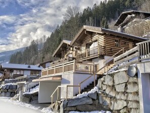 A wooden chalet with multiple balconies, stone steps, and a mountainous backdrop. - Schoneben Alpine Holiday Home (Wald im Pinzgau)