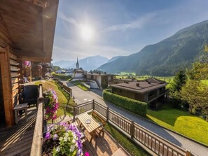 A wooden building with a balcony overlooking a village and mountains. - Schoneben Alpine Holiday Home (Wald im Pinzgau)