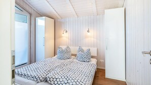 Een slaapkamer met een bed, twee wandlampen, een kledingkast en een deur.