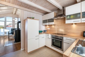 Eine moderne Küche mit weißen Schränken, einem eingebauten Ofen und einem großen Fenster.