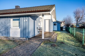 Eingeschossiges Haus mit der Nummer 29 an der Seite, einer Holzterrasse und einem umzäunten Garten.
