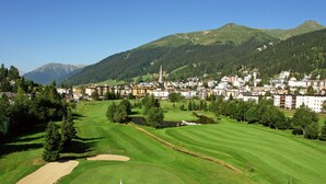 Ein Golfplatz mit Fahnenstange, Bunkern und einem Teich.