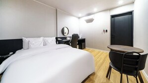 A hotel room with a bed, a desk, a chair, and a small table. - From H Dongbaek Hotel By Kwon Geoje Okpo (Geoje)