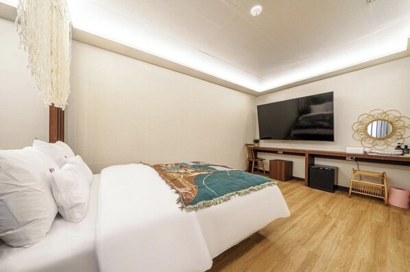 A hotel room with a bed, a desk, a television, and a mirror.