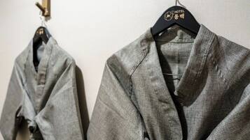 Two grey robes hanging on black hangers with a hotel logo.