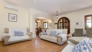 Amplia sala de estar con dos sofás, una zona de comedor y un gran ventanal de arco.