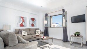 Ein modernes Wohnzimmer mit einem grauen Sofa, einem Couchtisch und Kunstwerken an den Wänden.