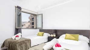 Ein Hotelzimmer mit zwei Betten, einem großen Fenster und Blick auf Gebäude.