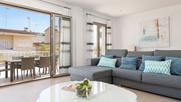A modern living room with a grey sofa, a glass coffee table, and a balcony with outdoor furniture. - Ca Na Xisca 2 - Apartment In Can Picafort (Can Picafort, Illes Balears)