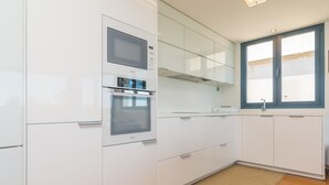 A modern kitchen with white cabinetry, a built-in oven, and a microwave. - Llevant - Apartment In Portocolom. Free Wifi (Portocolom, Illes Balears)