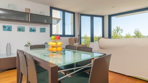 A modern room with a glass dining table, a sofa, and a bed. - Llevant - Apartment In Portocolom. Free Wifi (Portocolom, Illes Balears)