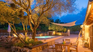 A pool area with lounge chairs, a table with chairs, and a dining table set up for outdoor dining.