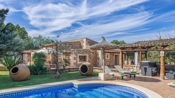 A swimming pool with a tiled edge, a stone building with a tiled roof, and outdoor seating with umbrellas. - Cas Mostatxet (sencelles) - Villa With Pool (Sencelles, Illes Balears)