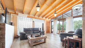 A spacious living room with wooden beams, a stone wall, and large windows. - Cas Mostatxet (sencelles) - Villa With Pool (Sencelles, Illes Balears)