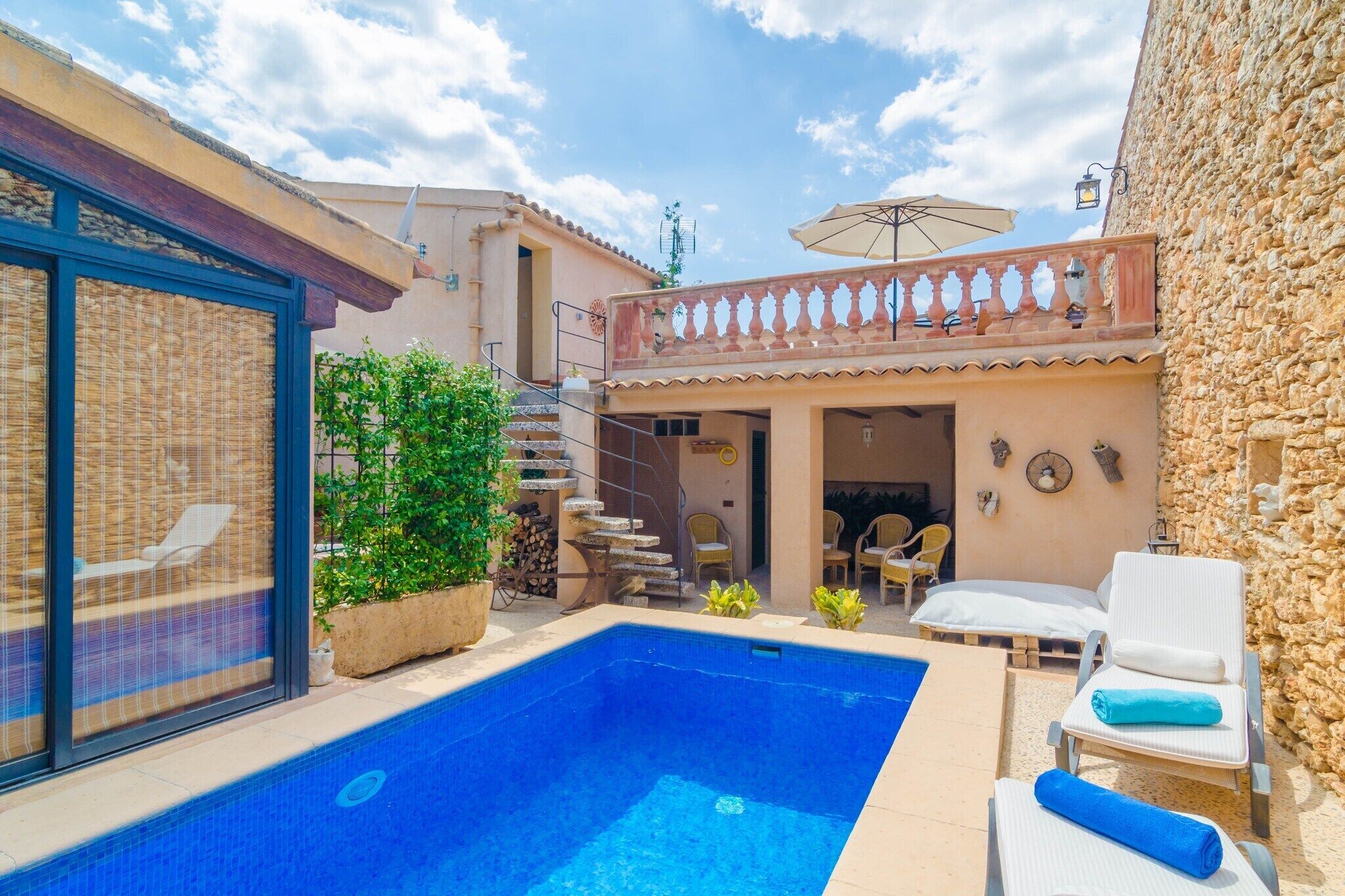 Piscina con sillones de descanso y un porche techado.