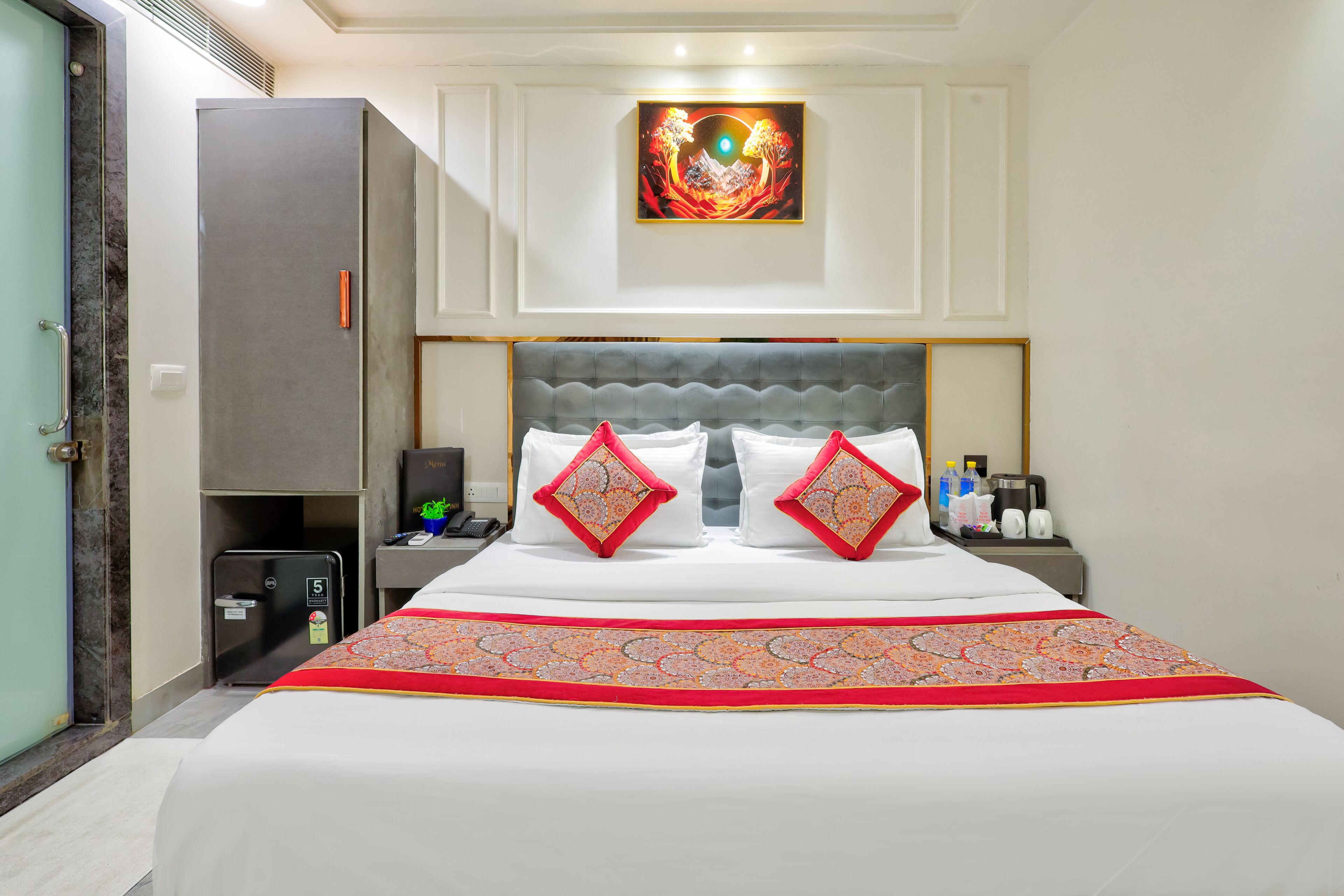 Ein Hotelzimmer mit Bett, Nachttisch, Wandbild und einer Tür.