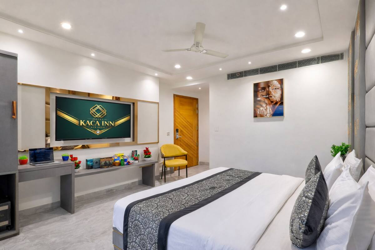 A modern hotel room with a bed, desk, television, and a ceiling fan.