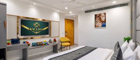 A modern hotel room with a bed, desk, television, and a ceiling fan.
