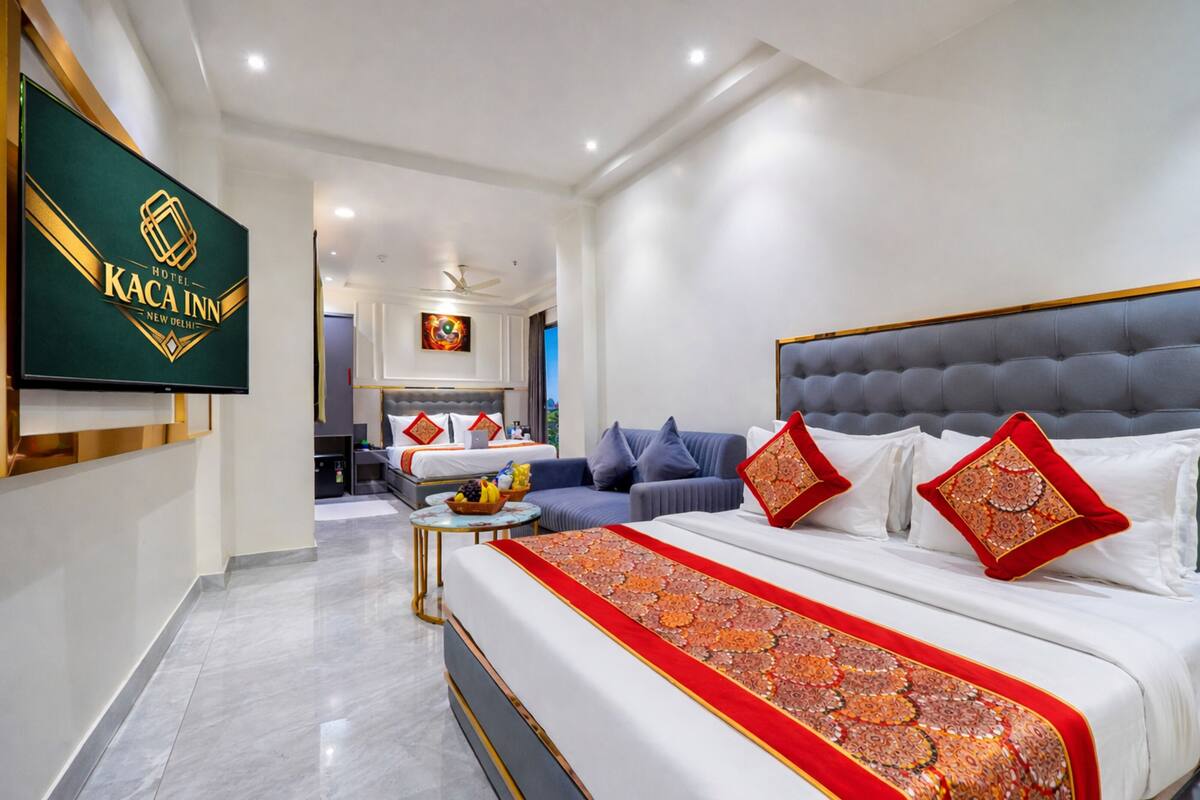 A hotel room with a large bed, a sofa, a TV, and a ceiling fan.