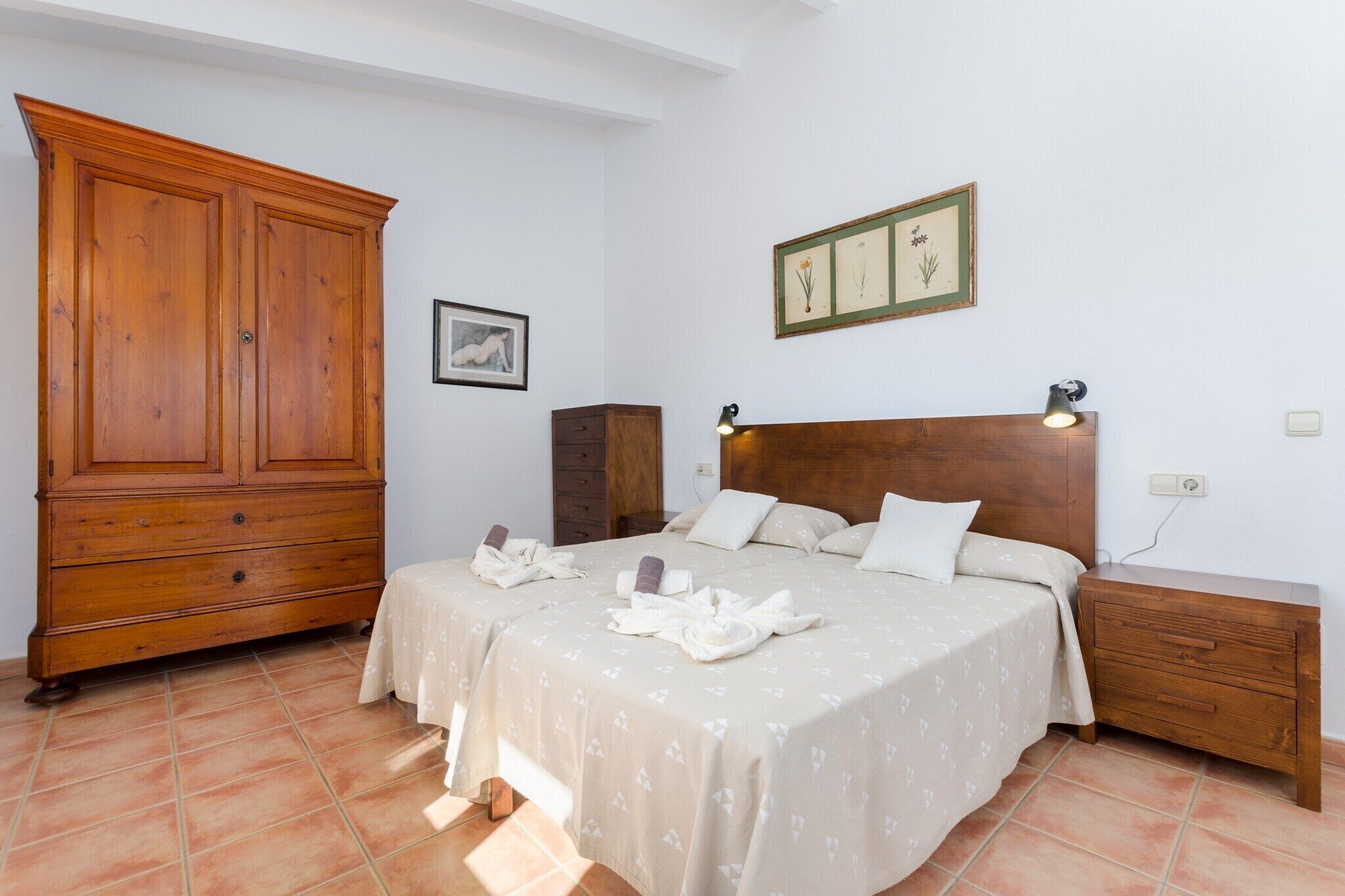 Un dormitorio con un armario de madera grande, una cama con cabecera y una mesita de noche con lámpara.