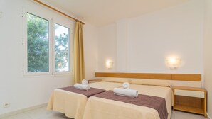 A twin room with two beds, a wooden headboard, bedside tables, and a window with curtains. - Massanet (1c) - Apartment In Canyamel. Free Wifi (Canyamel, Illes Balears)