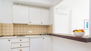 A compact kitchen with white cabinets, a built-in dishwasher, and a wooden countertop. - Massanet (1c) - Apartment In Canyamel. Free Wifi (Canyamel, Illes Balears)