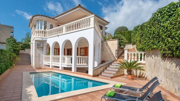 Una casa de dos plantas con piscina, zona de estar exterior y una escalera que lleva al nivel superior.
