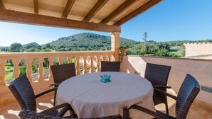 A covered outdoor seating area with wicker chairs and a table, overlooking a scenic landscape with hills and a clear sky. - Pula ViÑas - Villa With Private Pool. Free Wifi (Son Servera, Illes Balears)