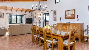 A dining area with a wooden table and chairs, a chandelier, and a television in the background. - Pula ViÑas - Villa With Private Pool. Free Wifi (Son Servera, Illes Balears)