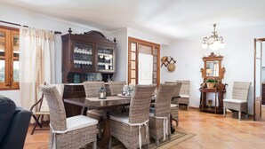 A dining area with a wooden table and wicker chairs, a cabinet with glass doors, and a mirror on the wall. - Es Cocons - Villa With Private Pool In Sineu (Sineu, Illes Balears)