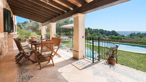 A covered outdoor dining area with a pool view, featuring a table and chairs, a potted plant, and a pergola structure. - Es Cocons - Villa With Private Pool In Sineu (Sineu, Illes Balears)
