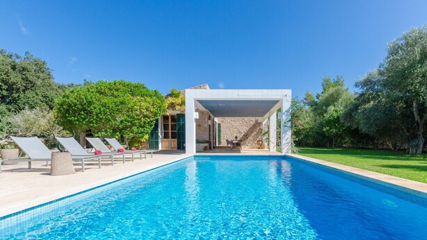 A swimming pool with lounge chairs and a covered area.