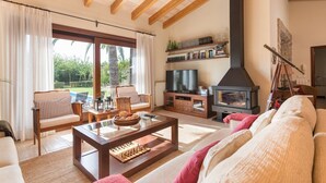 A living room with a fireplace, a television, and a bookshelf. - Finca Pou Nou - Villa With Private Pool In Inca (Inca, Illes Balears)
