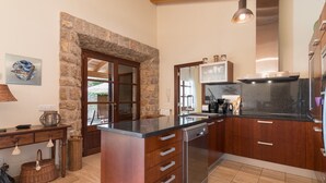 A modern kitchen with a stone archway, wooden cabinets, a stainless steel range hood, and a built-in dishwasher. - Finca Pou Nou - Villa With Private Pool In Inca (Inca, Illes Balears)