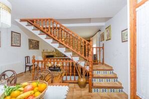Staircase leads to an upper level, flanked by artwork, with a dining area below.