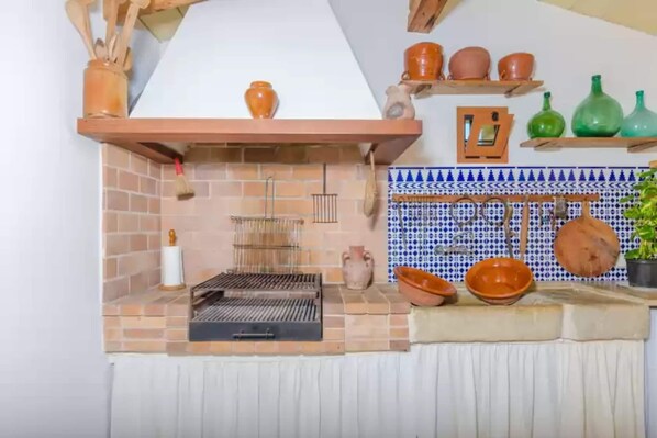 Enjoy cooking in this kitchen with an oven, shelves for storage, and a hanging rack for utensils.