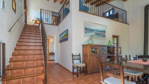 A spacious interior with a wooden staircase, a dining area with a large table and chairs, and a view of the upper floor. - Mercader - Villa With Private Pool In Alcúdia (Alcúdia, Illes Balears)
